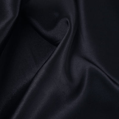 Smooth dark satin fabric texture close-up.