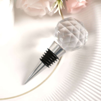 Crystal wine stopper with diamond-shaped top and stainless steel base.