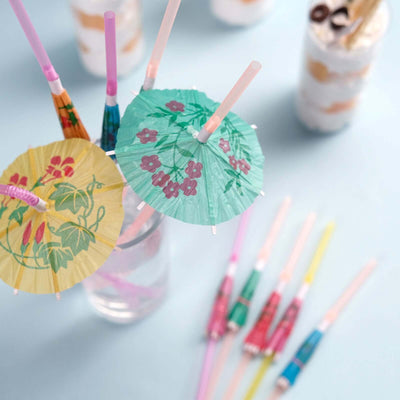 Colorful cocktail umbrellas in a glass with drinks in the background.