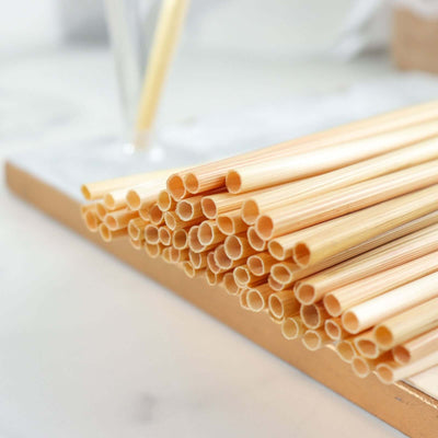 Natural bamboo straws stacked on a wooden surface.