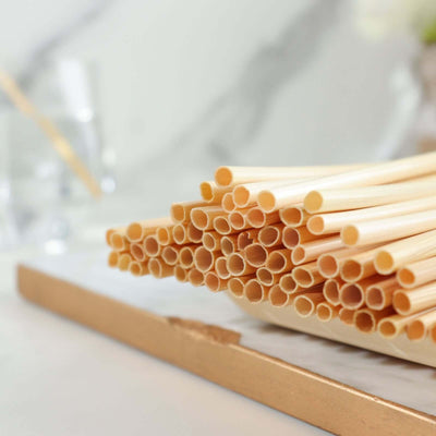 Natural bamboo straws stacked on a marble surface.