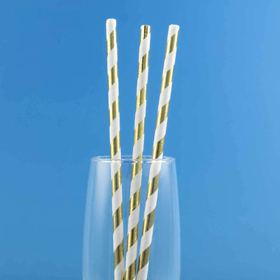 Gold-striped paper straws in a glass against a blue background.