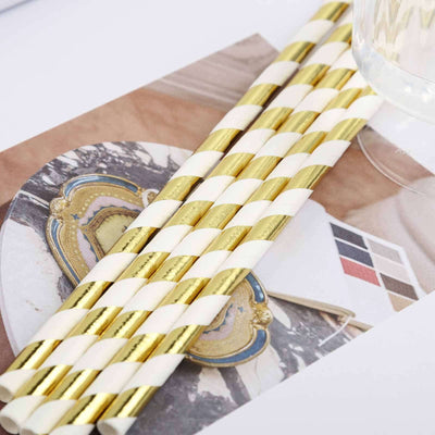 Gold and white striped paper straws on a decorative surface.