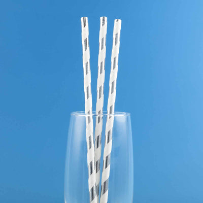 Three striped paper straws in a glass against a blue background.