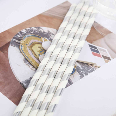 Decorative white and silver striped straws on a stylish tabletop background.