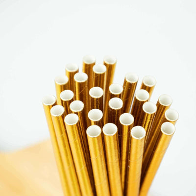Gold paper straws in a bundle against a plain background