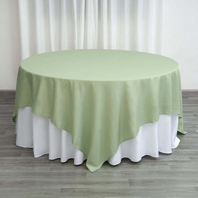 Round green tablecloth draped over a white table.