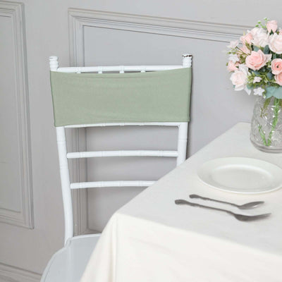 Green chair cover on a white chair beside a table with floral centerpiece.