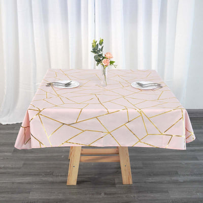 Pink geometric tablecloth with gold accents on a wooden table.