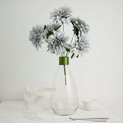 Decorative gray flowers in a clear vase on a white background.