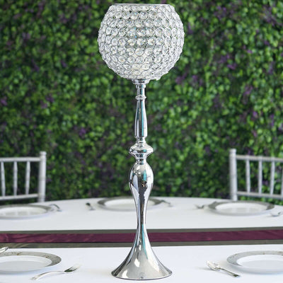 Elegant crystal candle holder on a table with greenery backdrop.
