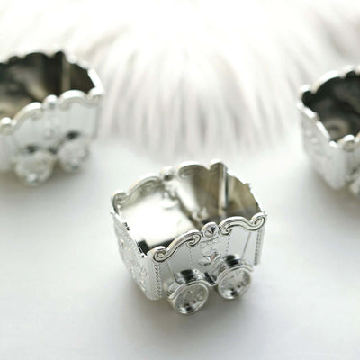 Silver baby carriage decorative trinket boxes arranged on a soft white surface.