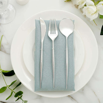 Silver cutlery set on a blue napkin atop a white plate.