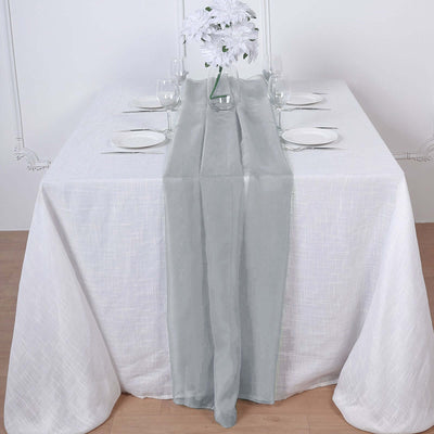 Elegant gray table runner on a white table setting with glassware and flowers.