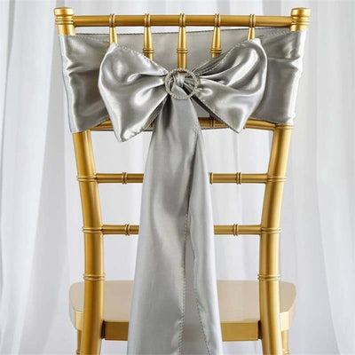 Silver satin chair sash with bow on a gold chiavari chair.