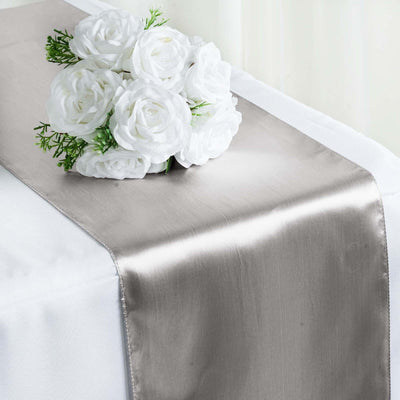 Elegant satin table runner with artificial white roses arrangement.