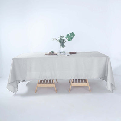 Light gray tablecloth draped over wooden table with decor