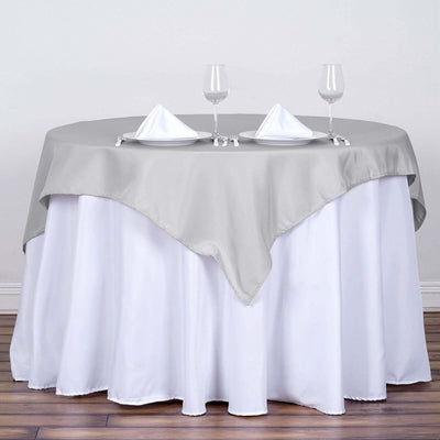 Elegant round table set with gray and white tablecloths and wine glasses.