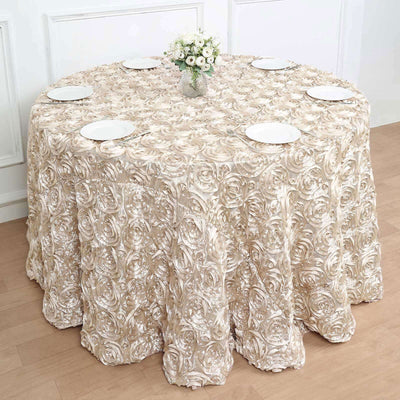 Elegant round table covered with a floral beige tablecloth, set for dining.