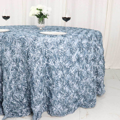 Elegant blue rose-patterned tablecloth on a dining table with wine glasses.