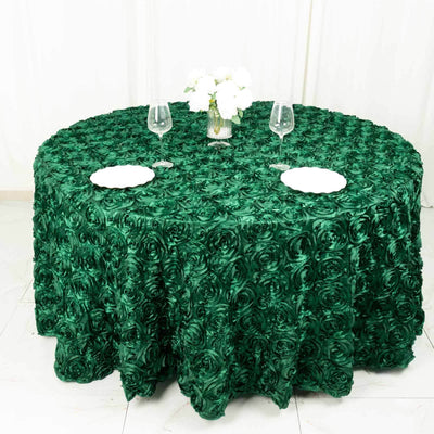Green rose-pattern round tablecloth on a dining table with plates and glasses.