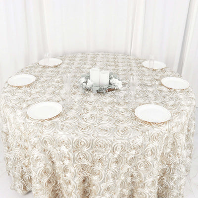 Elegant rose-patterned tablecloth on a round table with plates and candles.