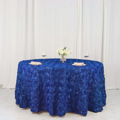 Blue rose-patterned tablecloth on a round table with floral centerpiece and glasses.