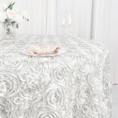 Elegant silver rose-patterned tablecloth with napkin and glassware.