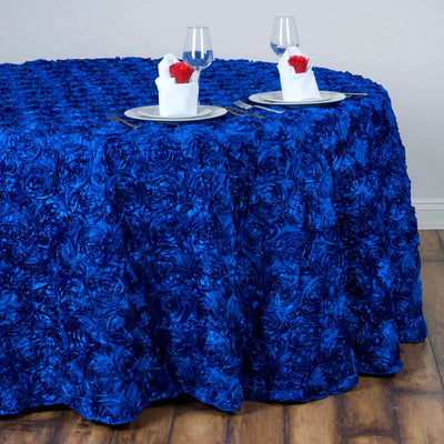 Elegant blue rose-patterned tablecloth on a dining table with glassware and napkins.
