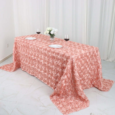 Peach rose-patterned tablecloth on a dining table with wine glasses and plates.