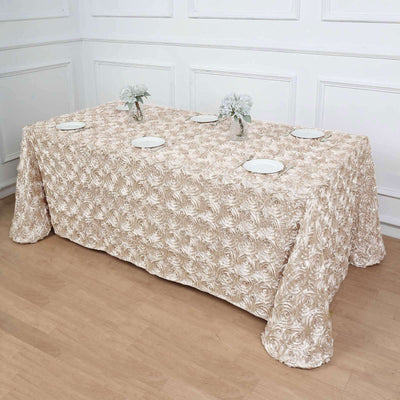 Elegant rose-patterned tablecloth draped over a table with plates and flowers.