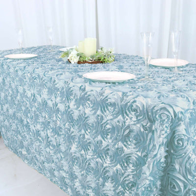 Blue rose-patterned tablecloth on a dining table with plates and decorations.