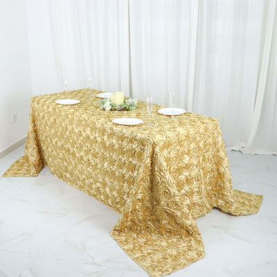 Elegant gold floral tablecloth draped over a table with plates and decor.