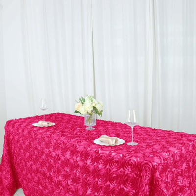 Pink rose-patterned tablecloth on a dining table with floral arrangement and glasses.
