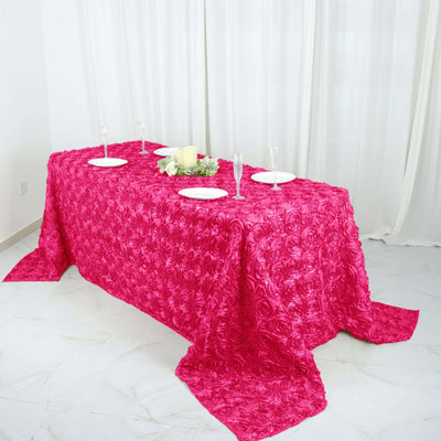 Table set with a vibrant pink rose-patterned tablecloth and elegant dinnerware.