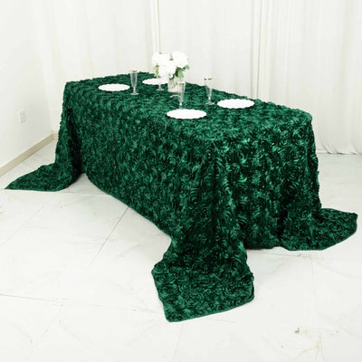 Green rose-pattern tablecloth draped over a table with plates and flowers.