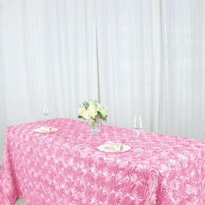 Pink rose-patterned tablecloth on a dining table with floral centerpiece and glasses.