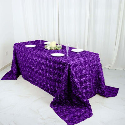 Purple rose-patterned tablecloth draped over a table with white plates.