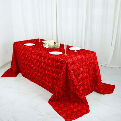 Red rose textured tablecloth on a dining table with plates and decorative centerpiece.
