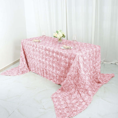 Pink rose-patterned tablecloth draped over a table with floral centerpiece.