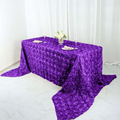 Purple rose-patterned tablecloth draped over a table with floral centerpiece.