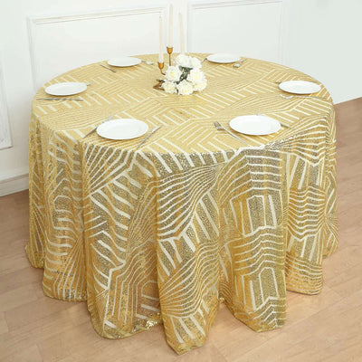 Gold geometric tablecloth draped over a round table with plates and flowers.