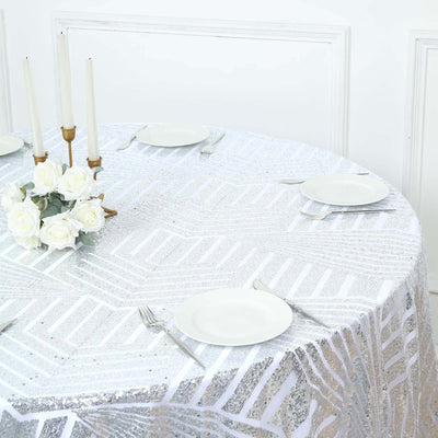 Round table set with a silver patterned tablecloth and white dinnerware.