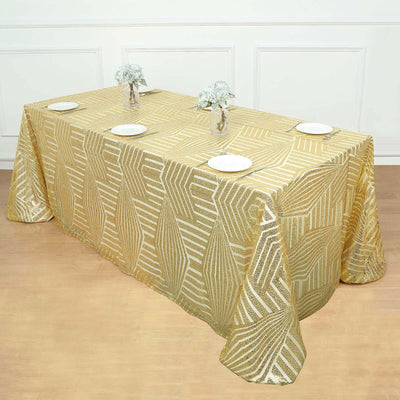 Gold leaf patterned tablecloth draped over a table with plates and floral centerpieces.