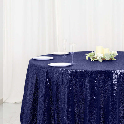Navy sequin tablecloth on a round table with plates and candles