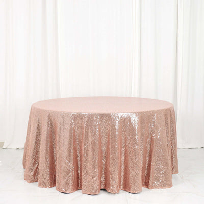 Rose gold sequin tablecloth on a round table against a white backdrop.