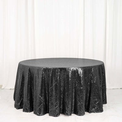 Round black sequin tablecloth on a plain backdrop.