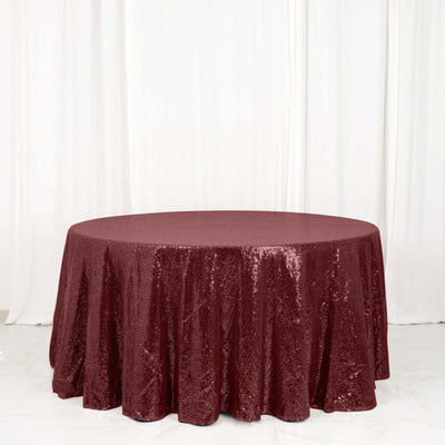 Burgundy sequin tablecloth on a round table against a white backdrop