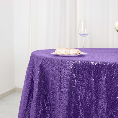 Purple sequin tablecloth draped elegantly on a table with a glass and napkin.