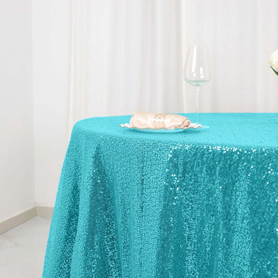 Turquoise sequin tablecloth on a table with a glass and napkin